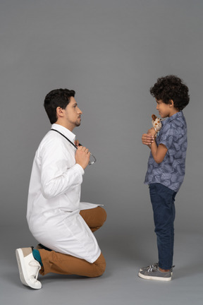 Menino segurando um brinquedo enquanto o médico olha para ele