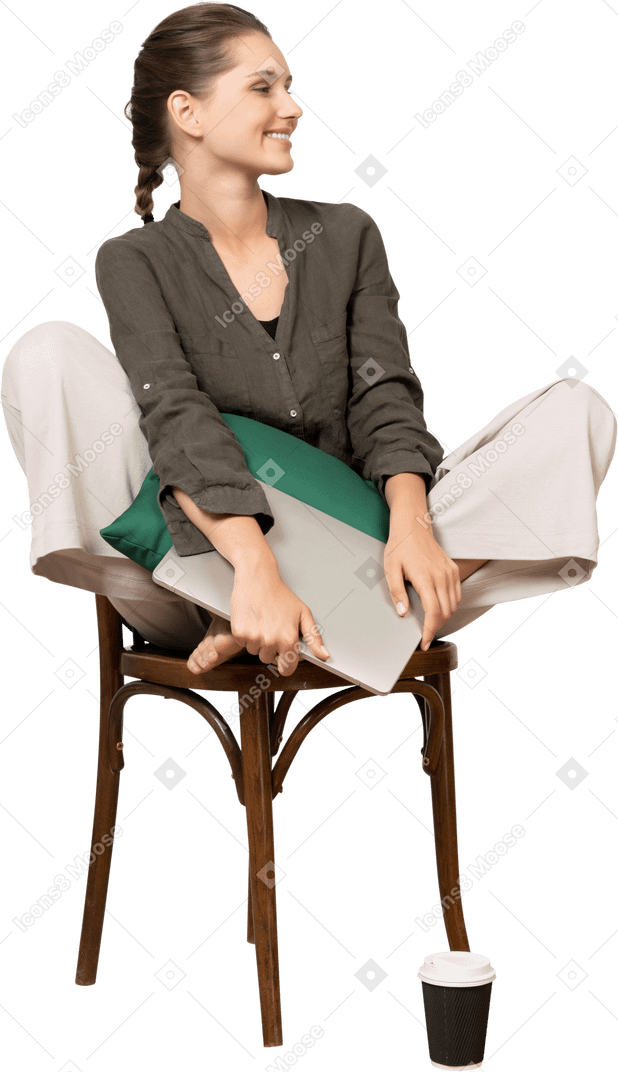 Vista frontale di una giovane donna sorridente seduta su una sedia e con in mano il suo laptop