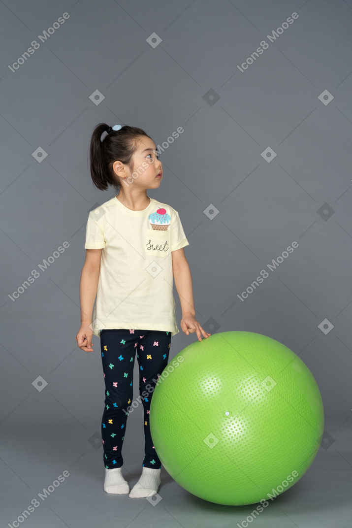Little girl standing by a green fitball