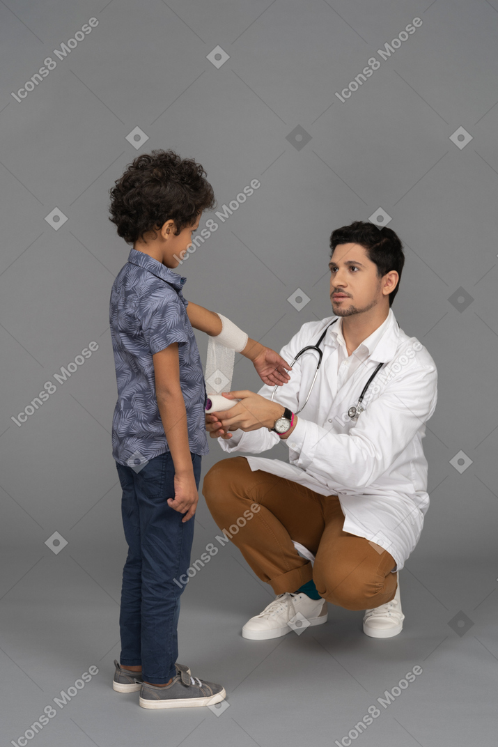 Médico enfaixando a mão de um menino