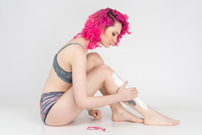 Young woman sitting on the floor and applying shaving cream