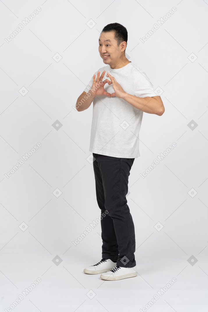 Side view of a man in casual clothes making heart with fingers