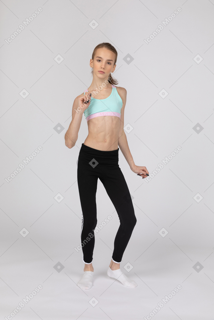 De cuerpo entero de una jovencita en ropa deportiva gesticulando y bailando