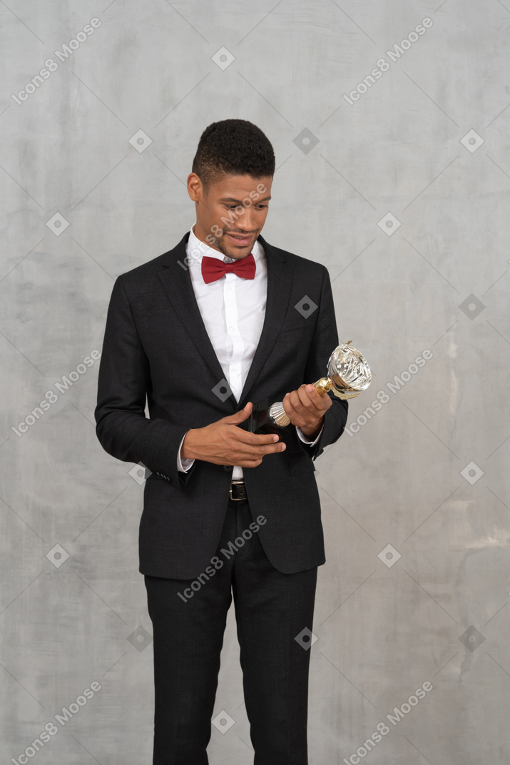 Homem sorridente de terno segurando um prêmio