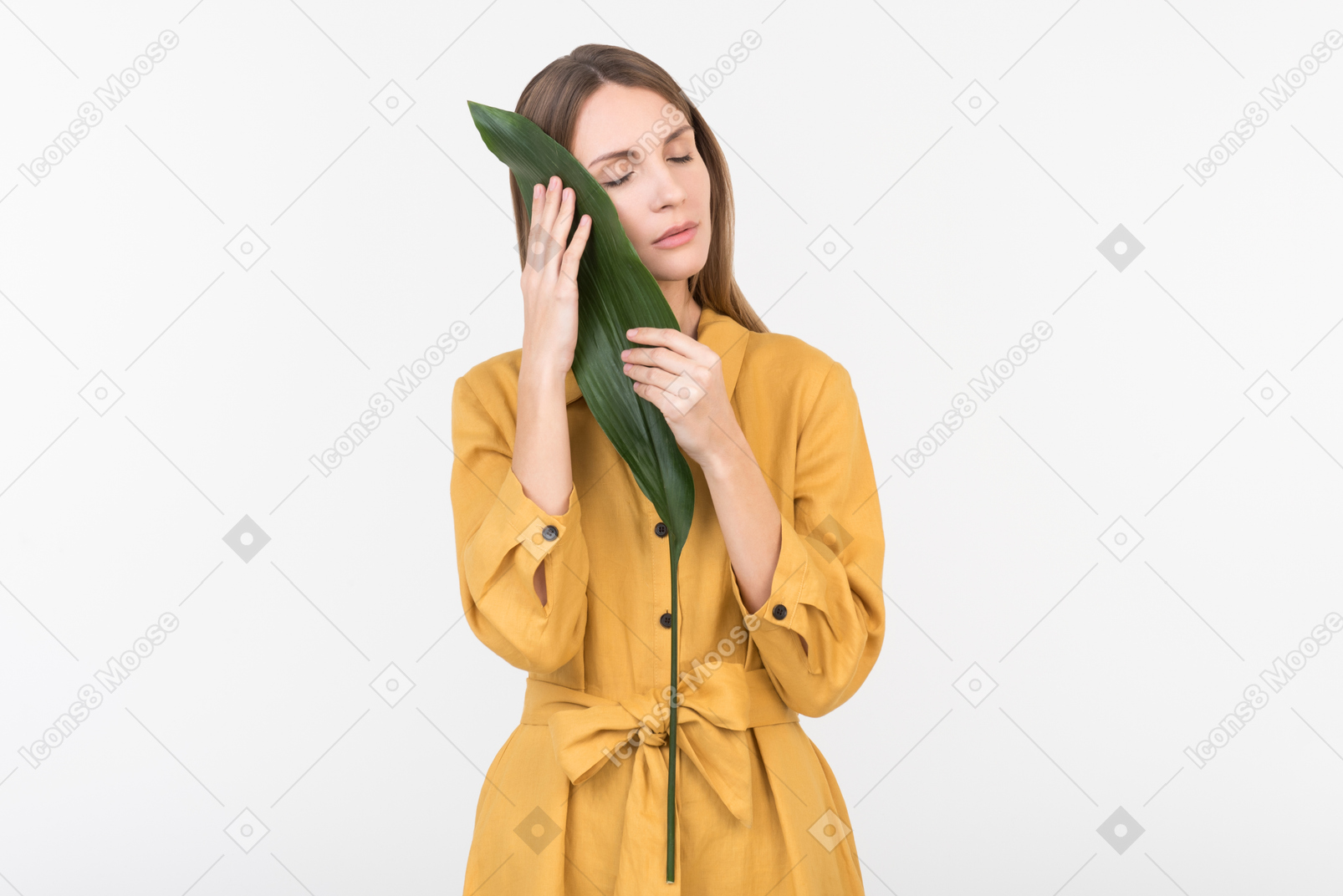 Joven mujer cerrando su rostro con hoja verde con los ojos cerrados