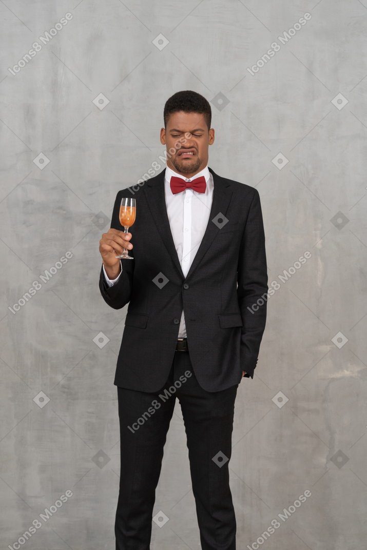 Empörter junger mann, der ein glas champagner betrachtet