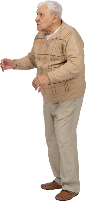 Vista lateral de un anciano enojado con ropa informal mirando hacia arriba