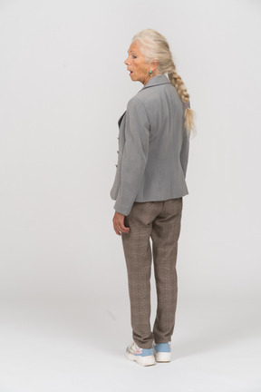 Vista posteriore di una donna anziana impressionata in giacca grigia