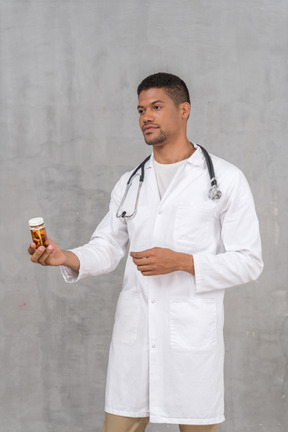 Doctor in lab coat showing a pill bottle