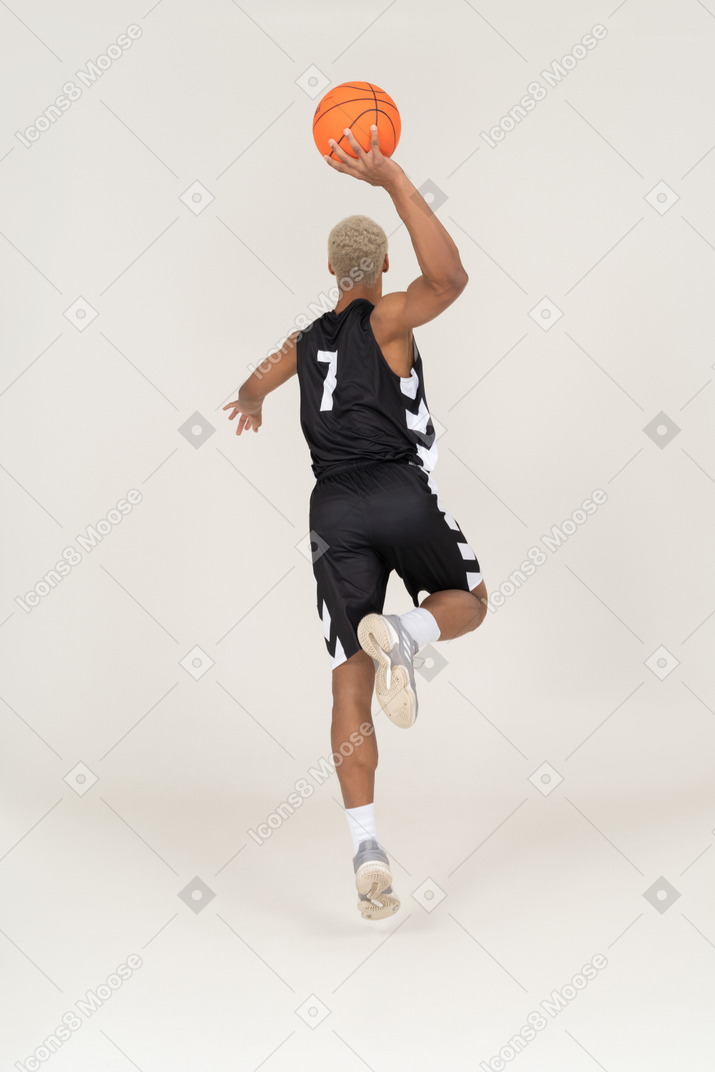 Back view of a young male basketball player scoring a point