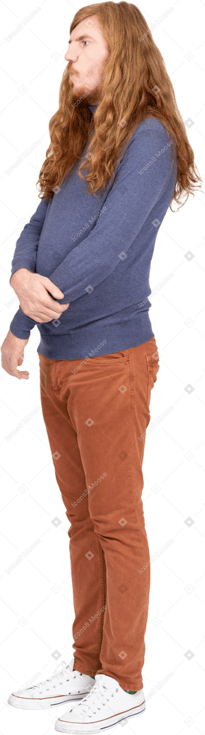 Seitenansicht eines jungen mannes in freizeitkleidung, der mit verschränkten armen steht