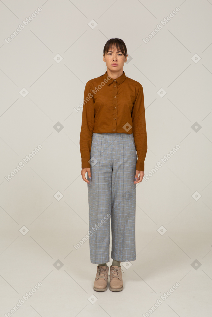 Front view of a puzzled young asian female in breeches and blouse standing still