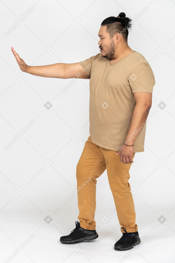 Serious asian man standing with outstretched hand making a stop gesture