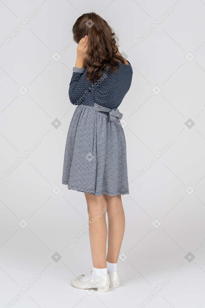 Back view of girl covering her ear with her hand