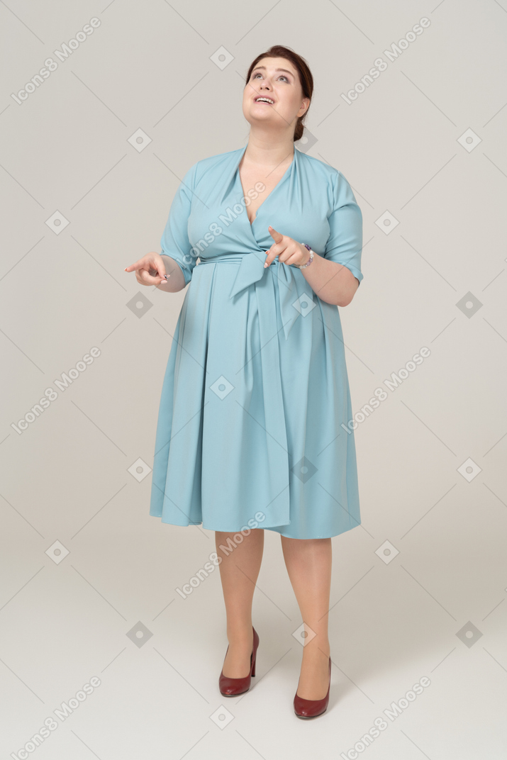 Вид спереди женщины в голубом платье, смотрящей вверх