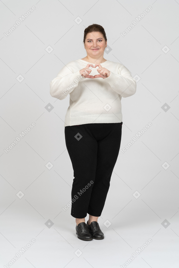 Plump woman in casual clothes making a heart gesture