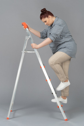 Young woman climbing a stepladder