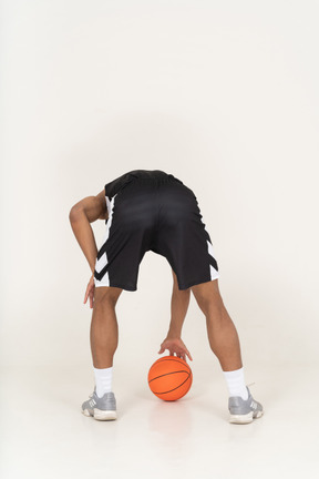 Back view of a young male basketball player touching ball