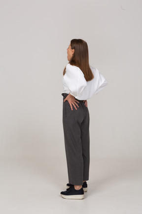 Vista posterior de tres cuartos de una señorita bostezo en ropa de oficina poniendo las manos en las caderas
