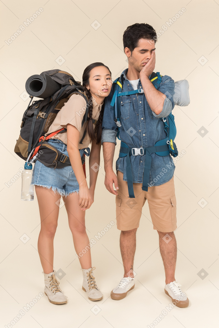 疲倦的看起来年轻人种间夫妇的徒步旅行者
