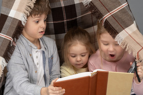 Children reading a book in a hut