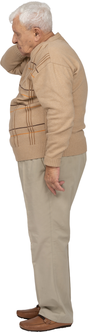 首に手を置いて立っているカジュアルな服装の老人の側面図