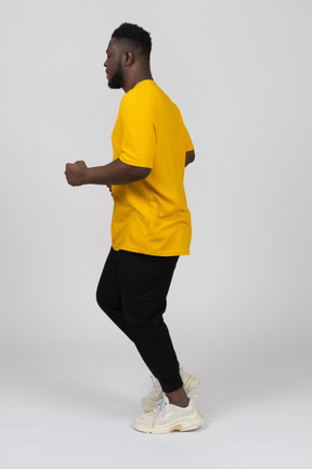Side view of a running young dark-skinned man in yellow t-shirt