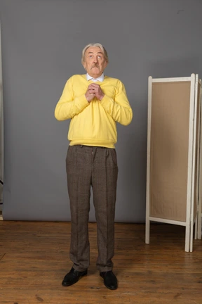 Front view of a surprised old man holding hands together