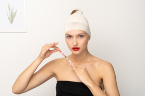 Young woman with bandaged head holding syringe