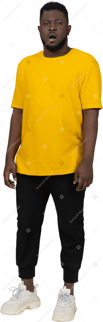 静止している黄色のtシャツを着た驚いた若い浅黒い肌の男の正面図