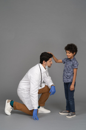 Niño poniendo su mano sobre la cabeza del doctor