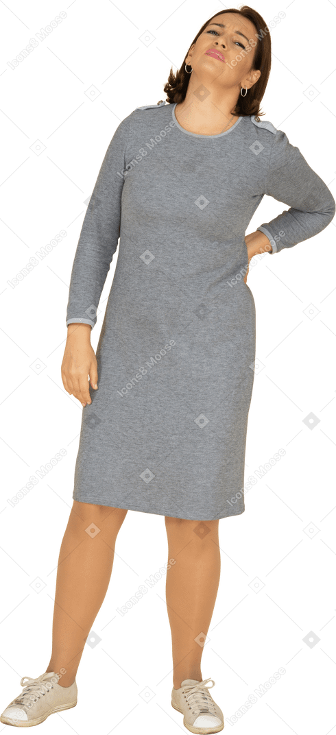 Vista frontale di una donna in abito grigio che soffre di dolore nella parte bassa della schiena