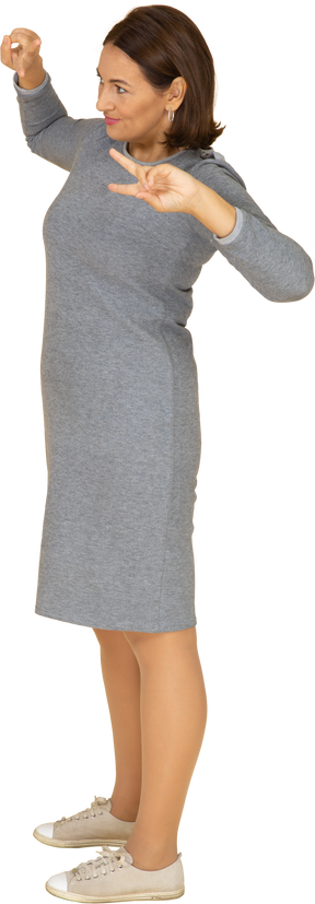 Vista lateral de uma mulher de vestido cinza gesticulando