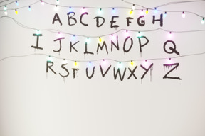 The alphabet written on a white wall with fairy lights