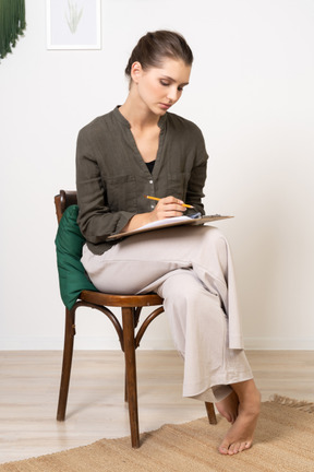 Vista frontale di una giovane donna premurosa seduta su una sedia mentre passa il test della carta