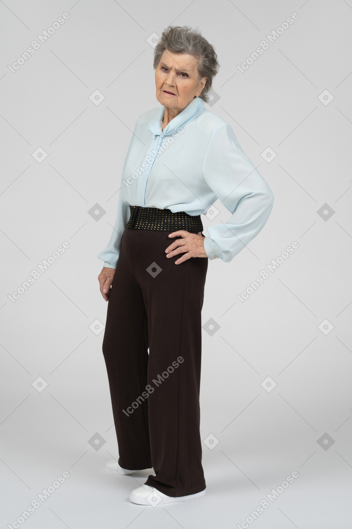 Vista di tre quarti di una donna anziana accigliata con una mano sull'anca