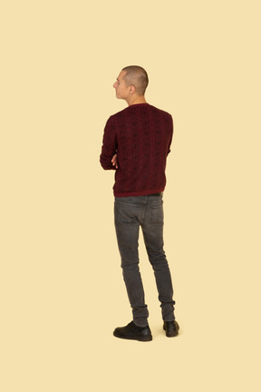 Back view of an offended young man dressed in casual clothes crossing his hands