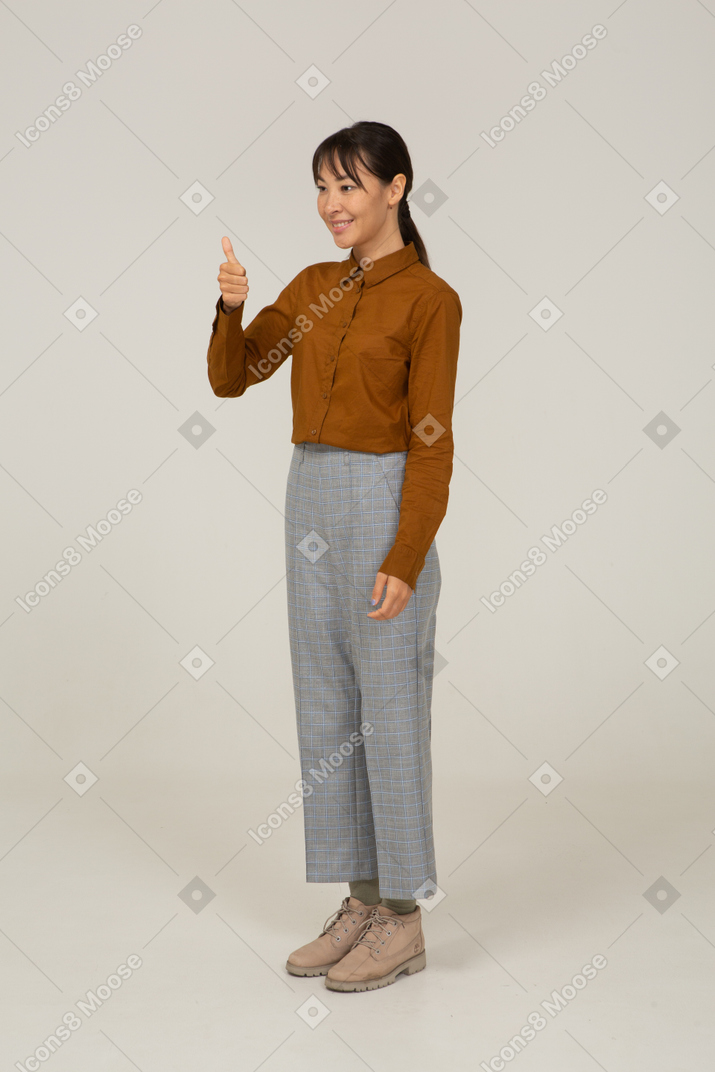 Three-quarter view of a young asian female in breeches and blouse showing thumb up