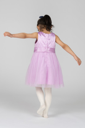 Chica con vestido rosa en movimiento con los brazos extendidos
