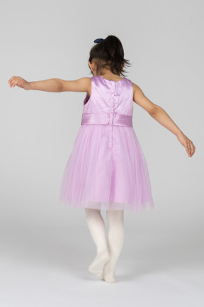 Girl in pink dress in motion with arms spread