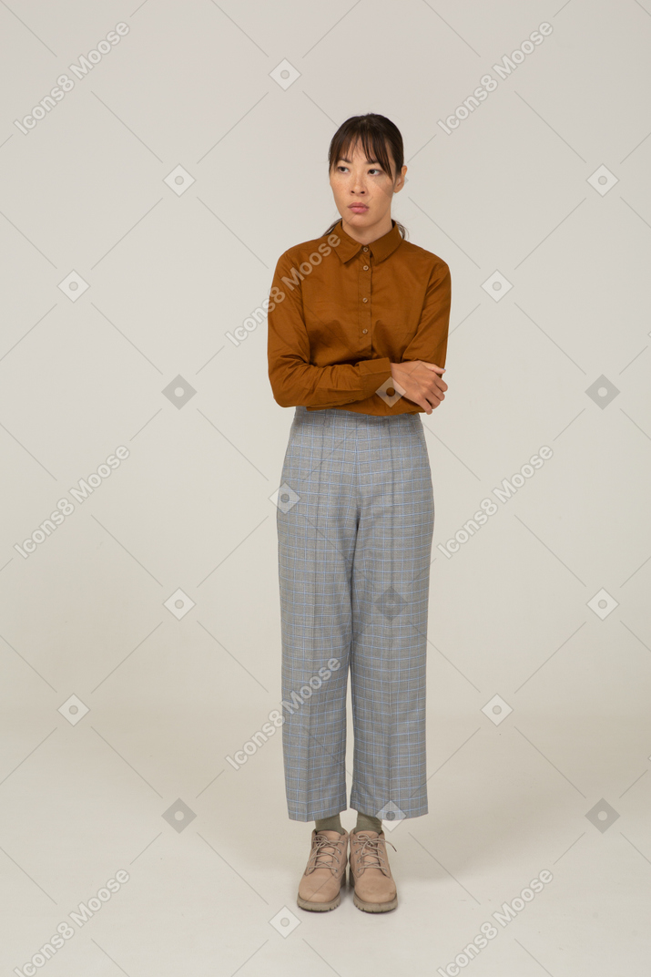 Vista frontal de una joven mujer asiática en calzones y blusa cruzando los brazos