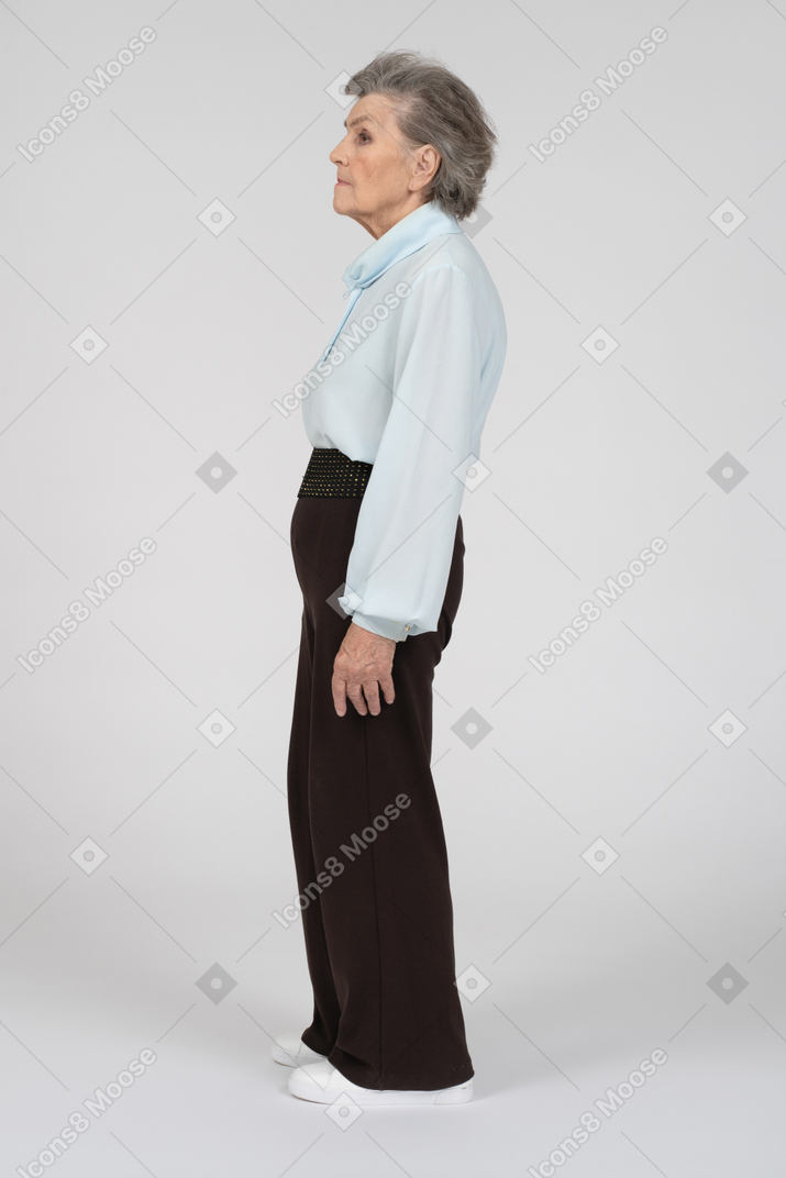 Side view of old woman standing and looking straight