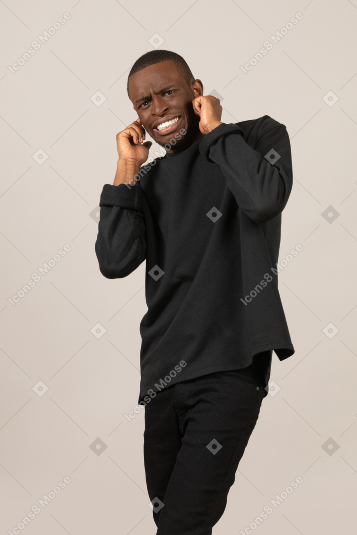 Man grinning and plugging ears