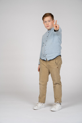 Front view of a boy showing v sign and looking at camera