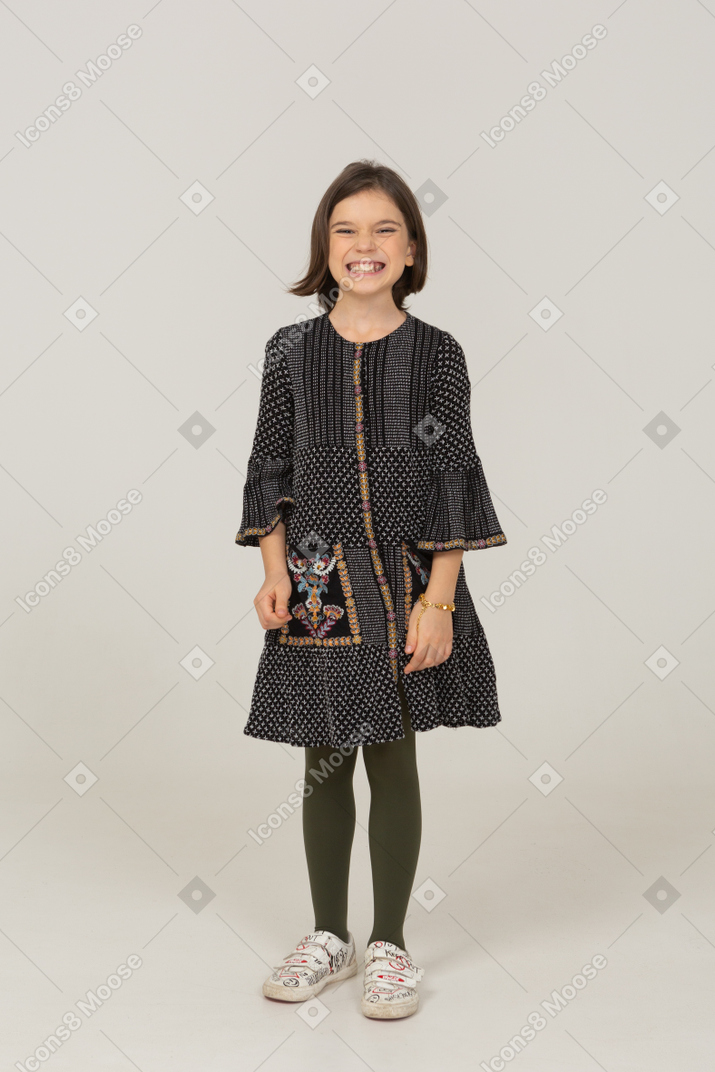 Front view of a smiling grimacing little girl in dress