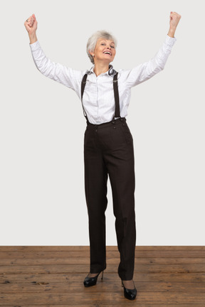 Mujer vestida formalmente celebrando con las manos en alto