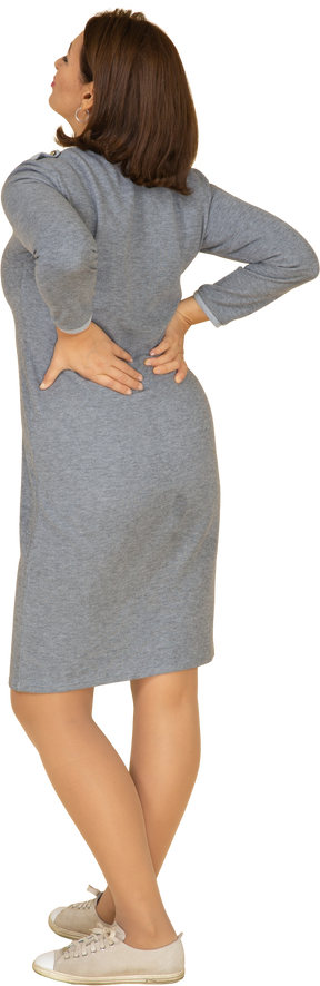Vista posteriore di una donna in abito grigio in piedi con le mani sui fianchi