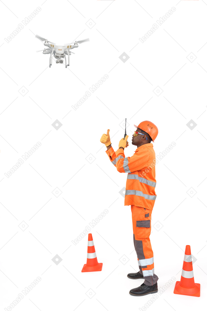 Construction worker with radio watching a drone and showing thumbs up