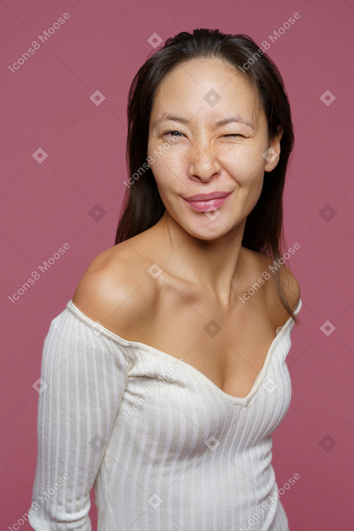 Vista de tres cuartos de una mujer de mediana edad guiñando un ojo y mirando a la cámara