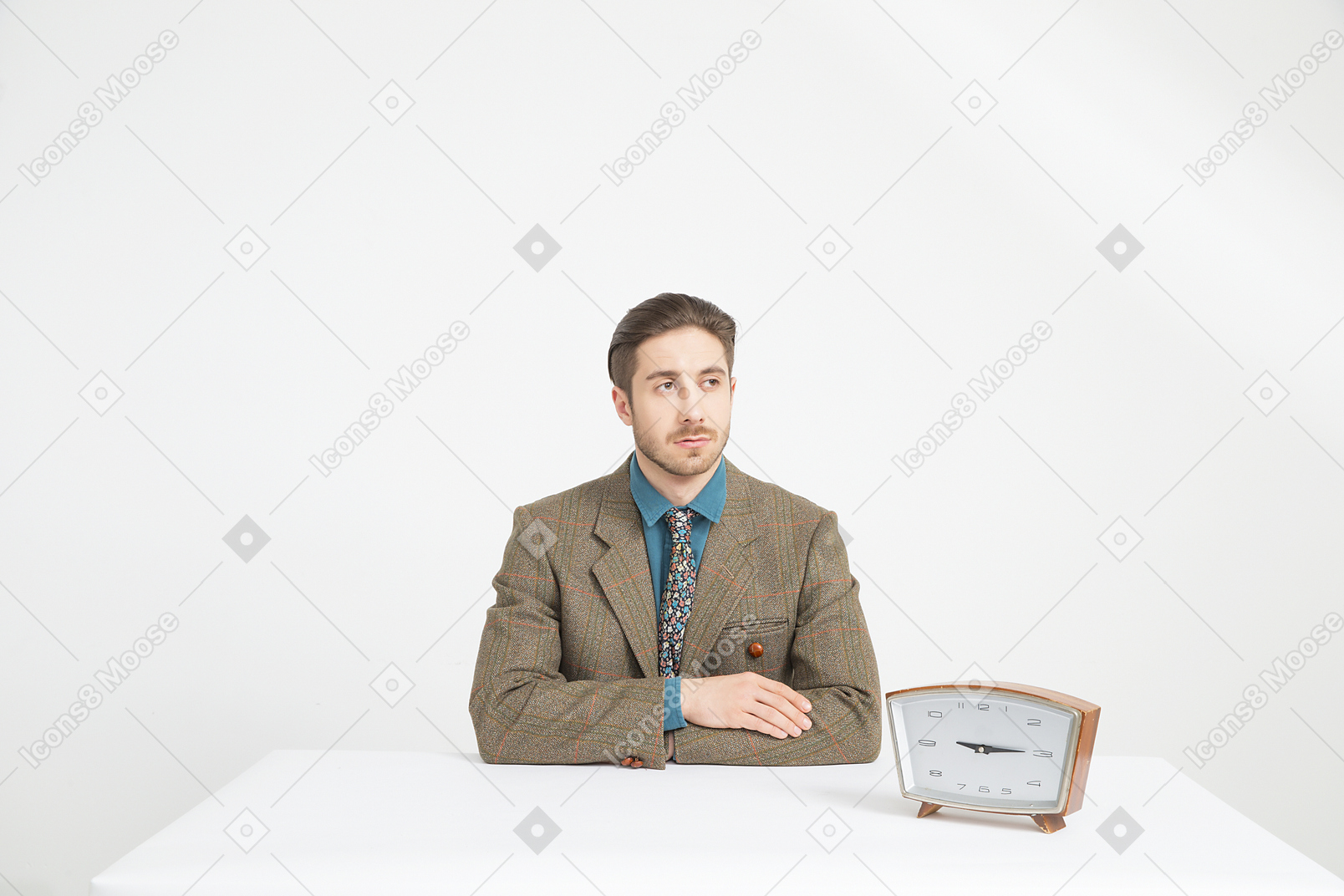 Handsome young man sitting near the clock with his hands folded
